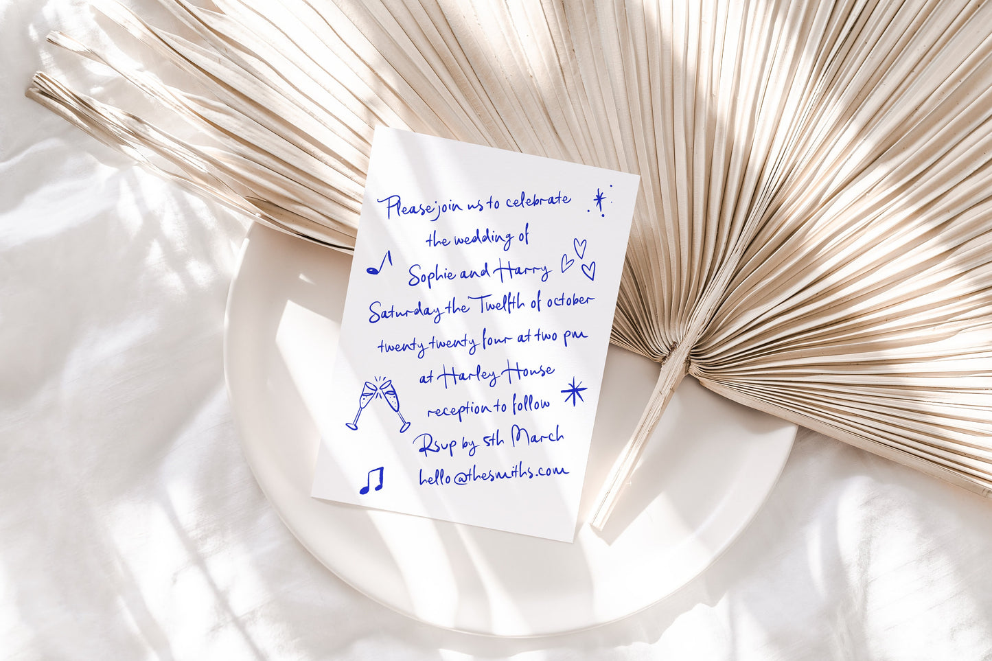 A handwritten wedding invitaiton featuring a white background and blue font