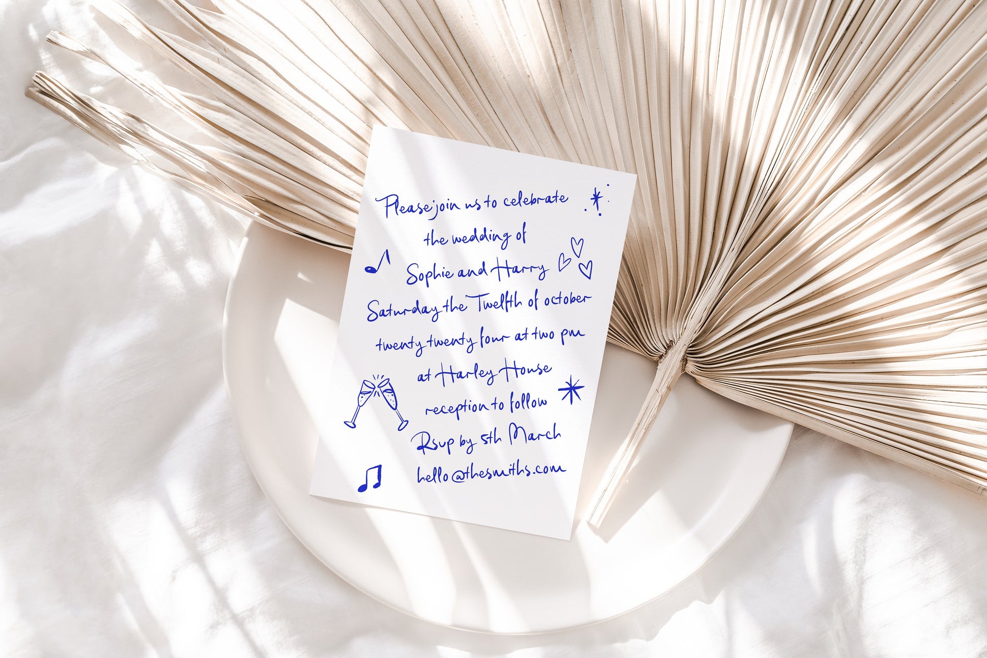 A handwritten wedding invitaiton featuring a white background and blue font